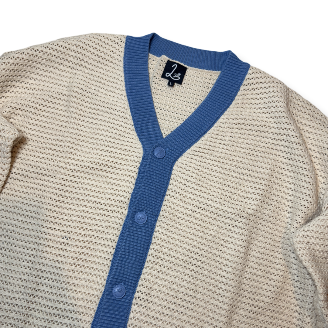 lion's tale studios knitwear knitted anti-logo no logo shirt light blue cream color button lion mena muria een voor allen voor een maluku molukken vertical stripes soft knit, breathable knitwear soft knit breathable knitwear cotton-blend quiet luxury, no-logo fashion, minimalist fashion Moluccan roots, heritage fashion, symbolic buttons unisex shirt, men’s knit shirt, women’s knitwear top cream and blue shirt, striped knit top, button-up knitwear designed in the Netherlands, Maluku inspired cardigan